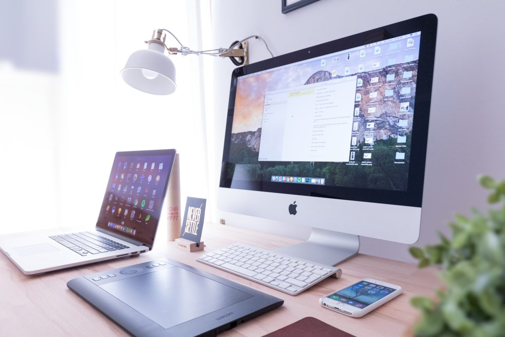 visuel d'un bureau avec deux ordinateurs et une tablette graphique