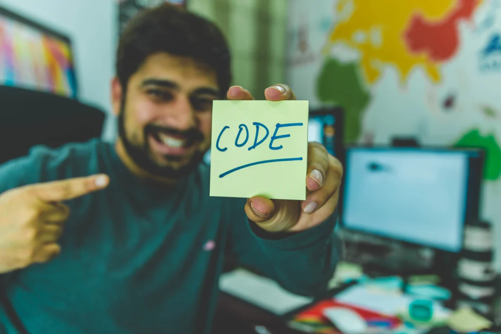 visuel d'un homme qui tient un post it avec le mot code dessus