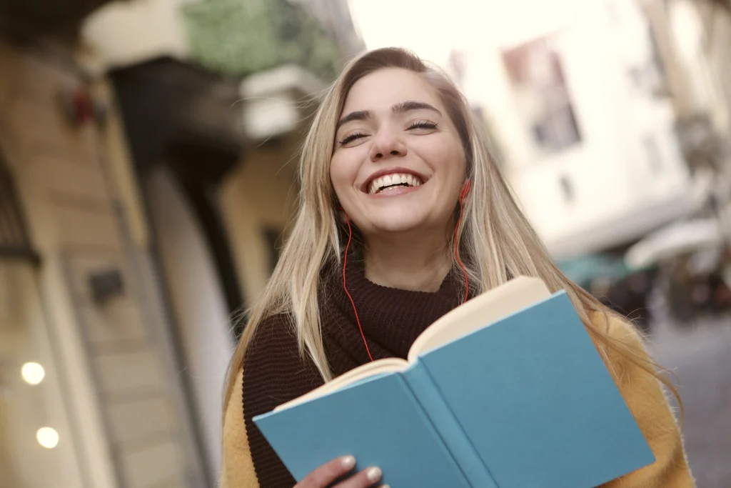 visuel d'une jeunne femme souriante qui tient un carnet dans ses mains